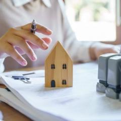 A women's hand next to a small wooden house