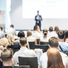 Man standing at the front of a white lecture room